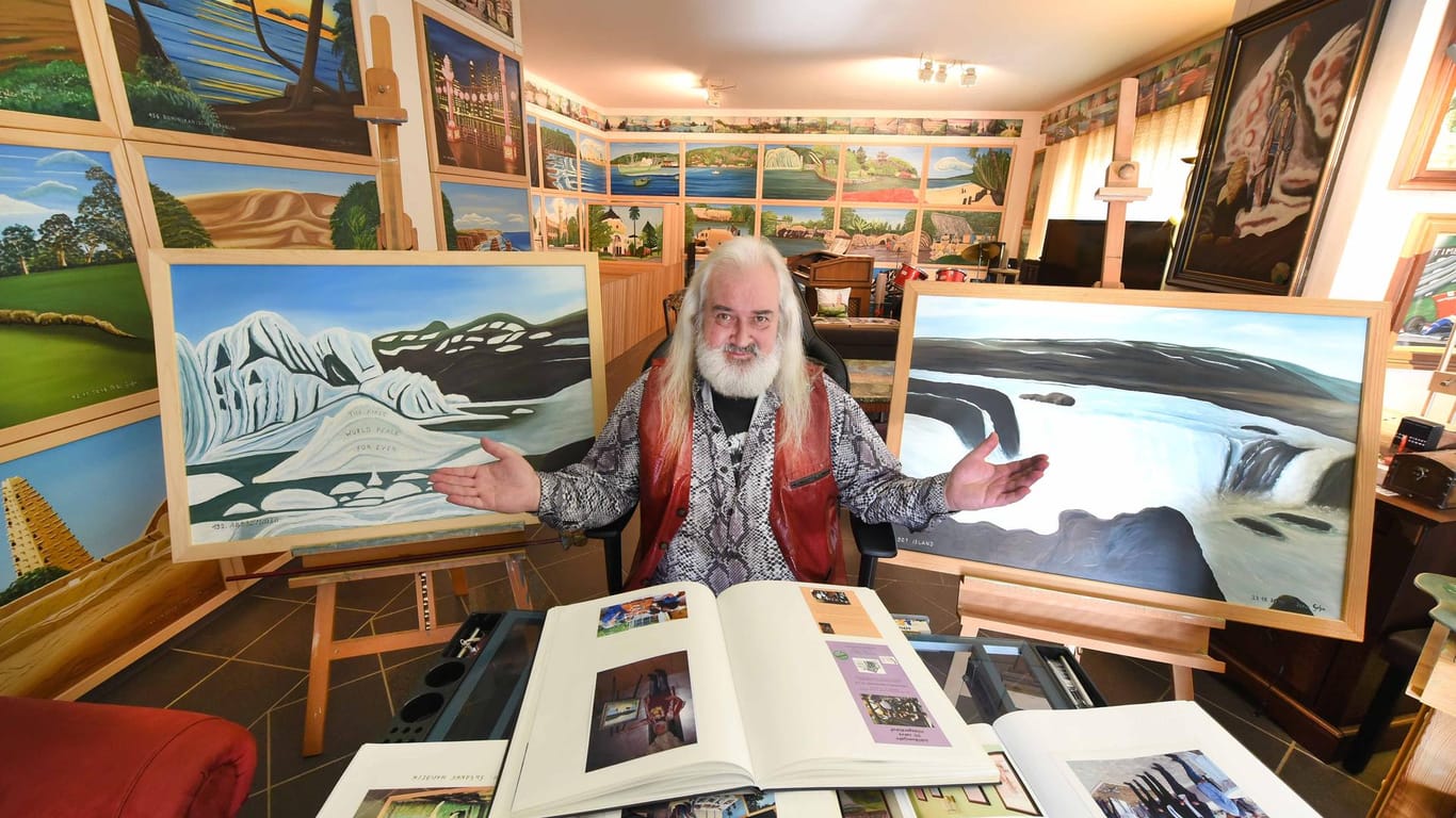 Der Künstler Peter Gehre sitzt in seinem Wohnzimmer, das er auch als Atelier, Musikzimmer und Büro nutzt: Die Bilder ergeben zusammengesetzt sein mit 192 Metern längstes Gemälde der Welt.