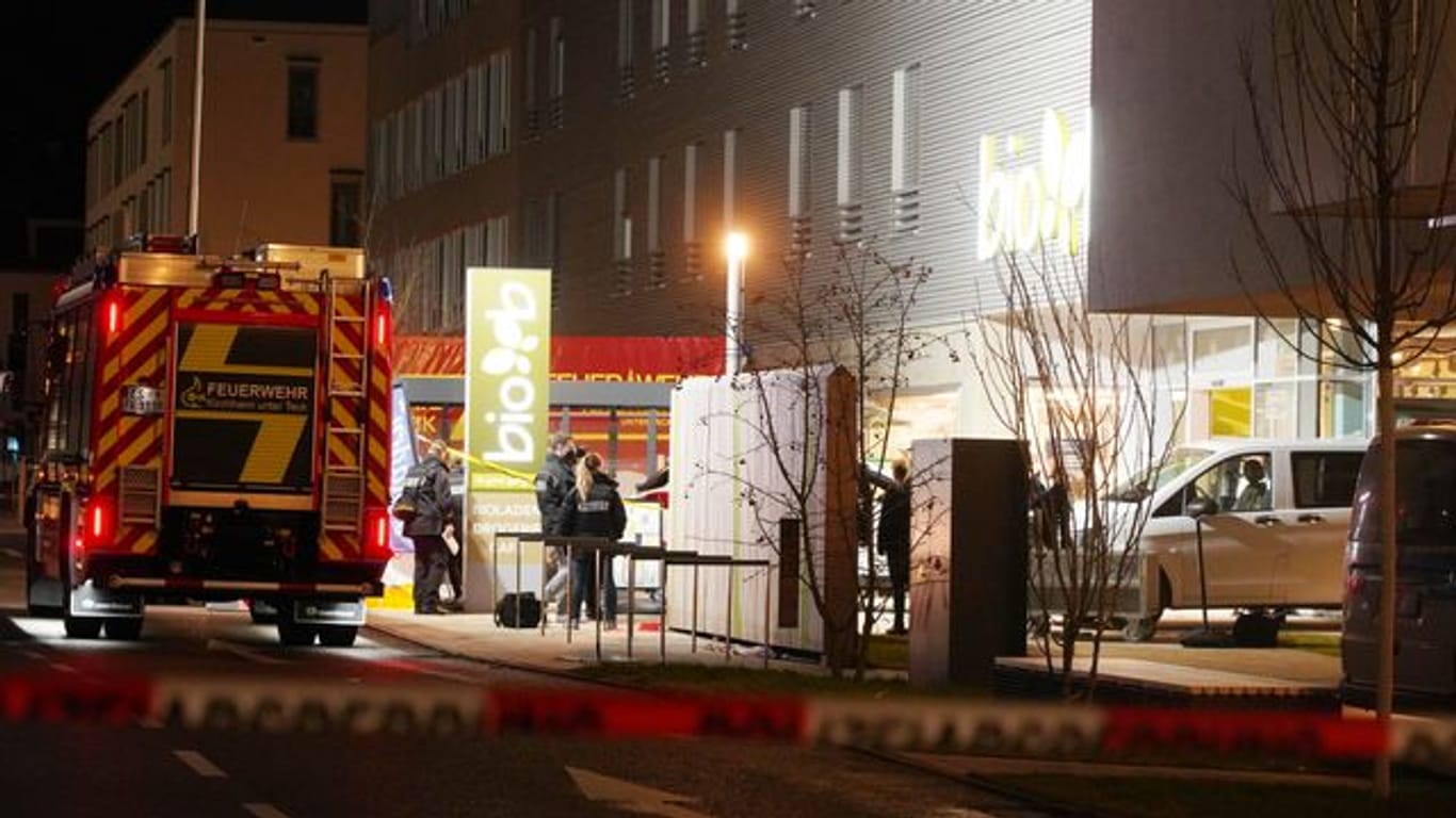 Polizisten und Feuerwehrleute stehen am Supermarkt in Kirchheim unter Teck, wo zwei Menschen durch Schüsse ums Leben gekommen sind.