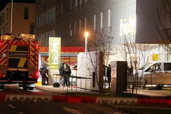 Polizisten und Feuerwehrleute stehen am Supermarkt in Kirchheim unter Teck, wo zwei Menschen durch Schüsse ums Leben gekommen sind.