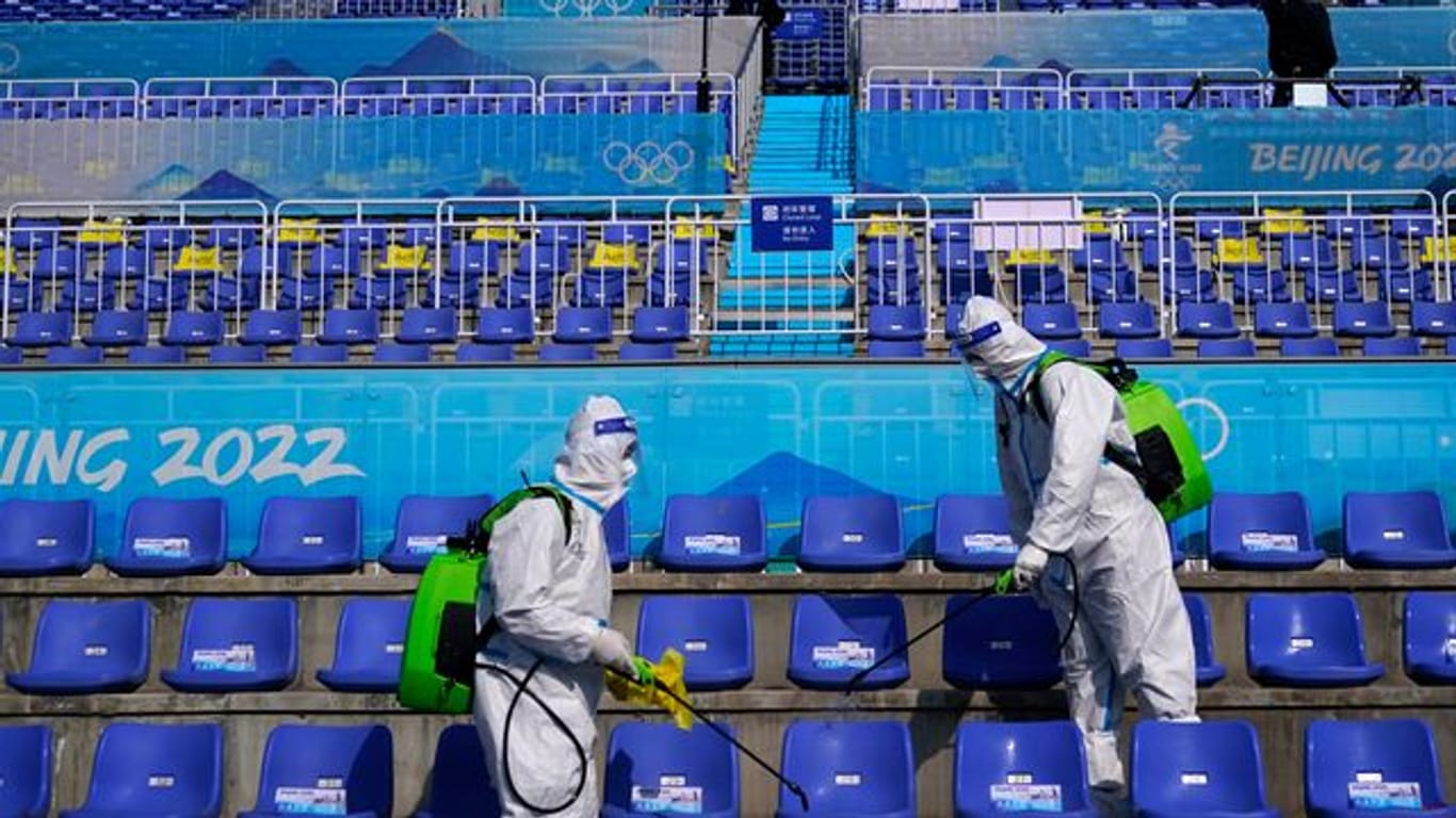 Arbeiter in Schutzkleidung desinfizieren Sitze nach dem Big-Air-Finale.