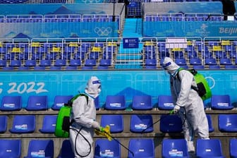 Arbeiter in Schutzkleidung desinfizieren Sitze nach dem Big-Air-Finale.