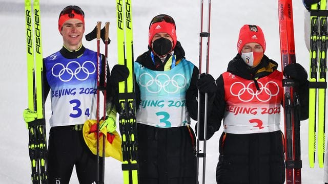 Die deutschen Nordischen Kombinierer Vinzenz Geiger (l-r), Julian Schmid und Manuel Faisst jubeln über die Silbermedaille.