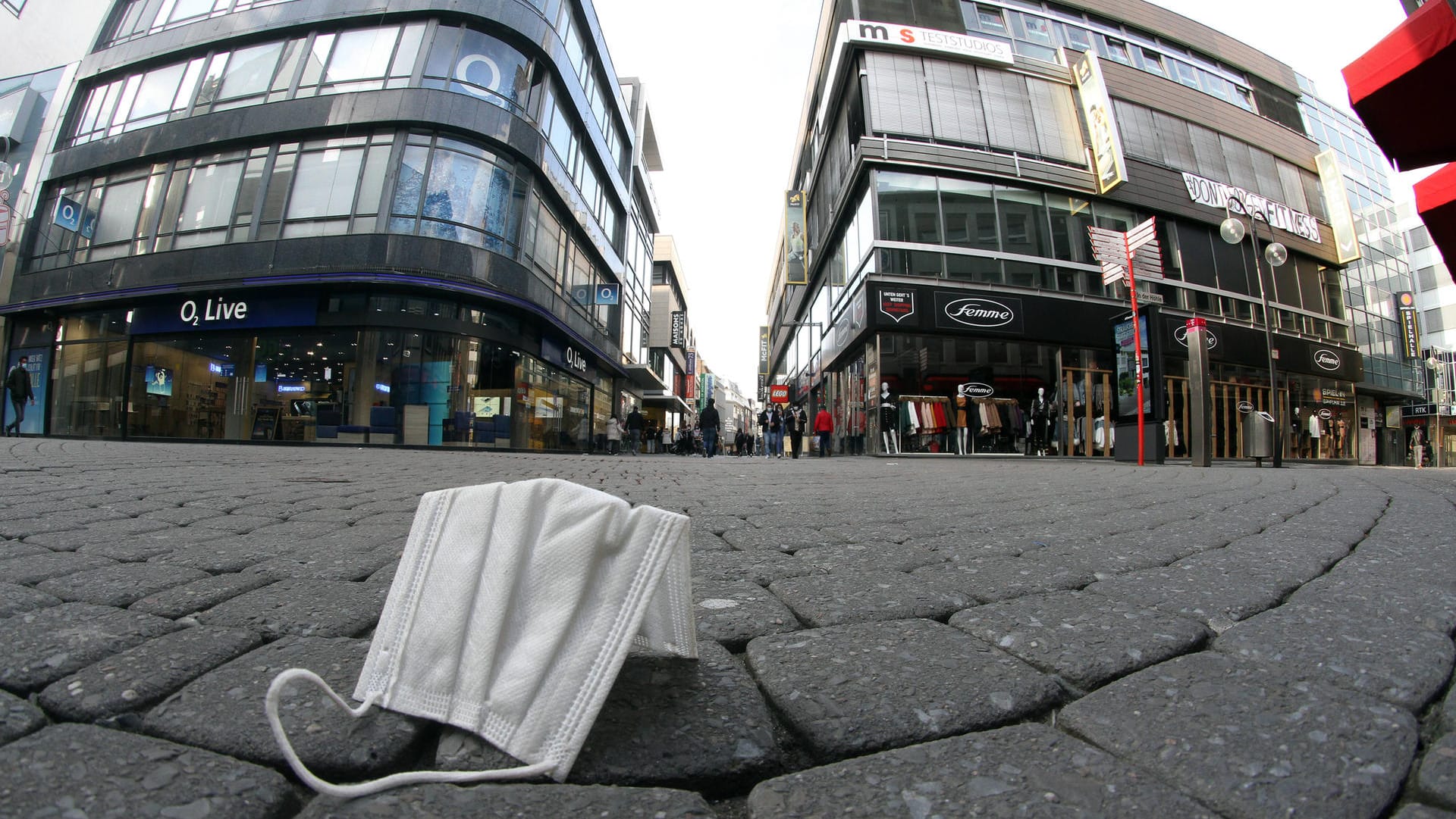 Getragene Mund-Nase-Bedeckungsmaske liegt in Köln auf der Straße (Symbolfoto): Kurz vor Beginn des Straßenkarnevals nimmt die Stadt die Maskenpflicht in den Fußgängerzonen und anderen belebten Plätzen zurück.