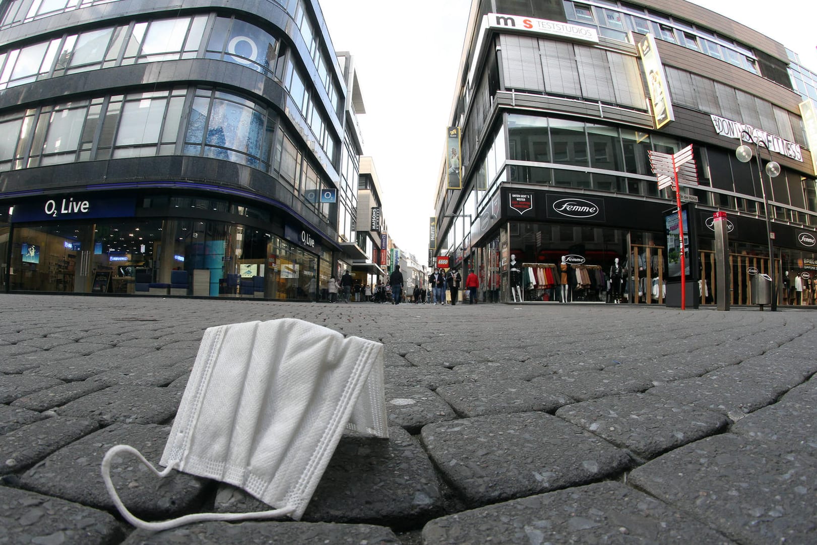 Getragene Mund-Nase-Bedeckungsmaske liegt in Köln auf der Straße (Symbolfoto): Kurz vor Beginn des Straßenkarnevals nimmt die Stadt die Maskenpflicht in den Fußgängerzonen und anderen belebten Plätzen zurück.