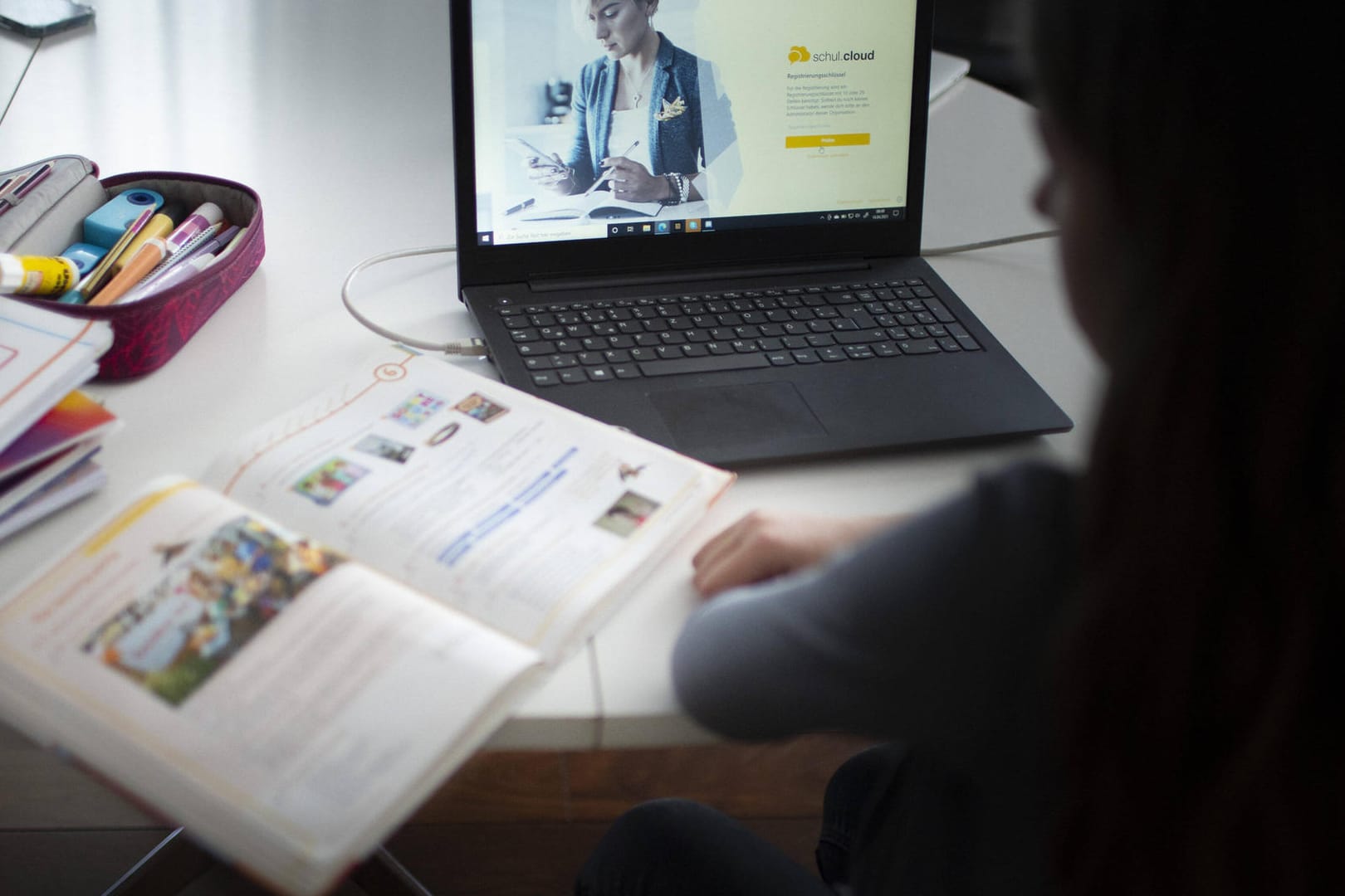 Eine Schülerin mit Laptop und Schulbüchern (Symbolbild): Gewerkschaften fordern mehr Hilfe vom Land für die Digitalisierung.