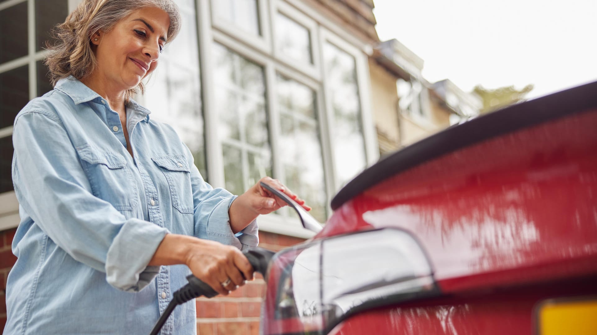 Eine Frau lädt ihr E-Auto (Symbolbild): Im Netz gibt es Dutzende Anbieter, denen Sie Ihre CO2-Einsparung verkaufen können.