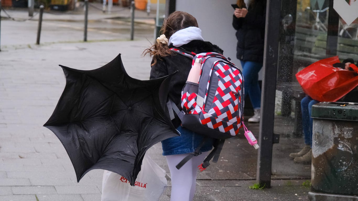 Ein Kind mit Rucksack im Unwetter in Düsseldorf (Archivbild): Am Freitag sollen die Schulen wieder öffnen.