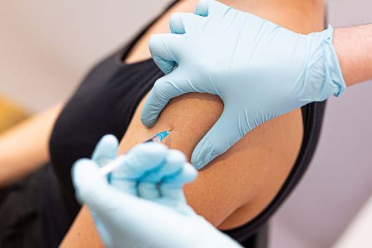 Eine Frau wird von einem Arzt gegen das Coronavirus geimpft.