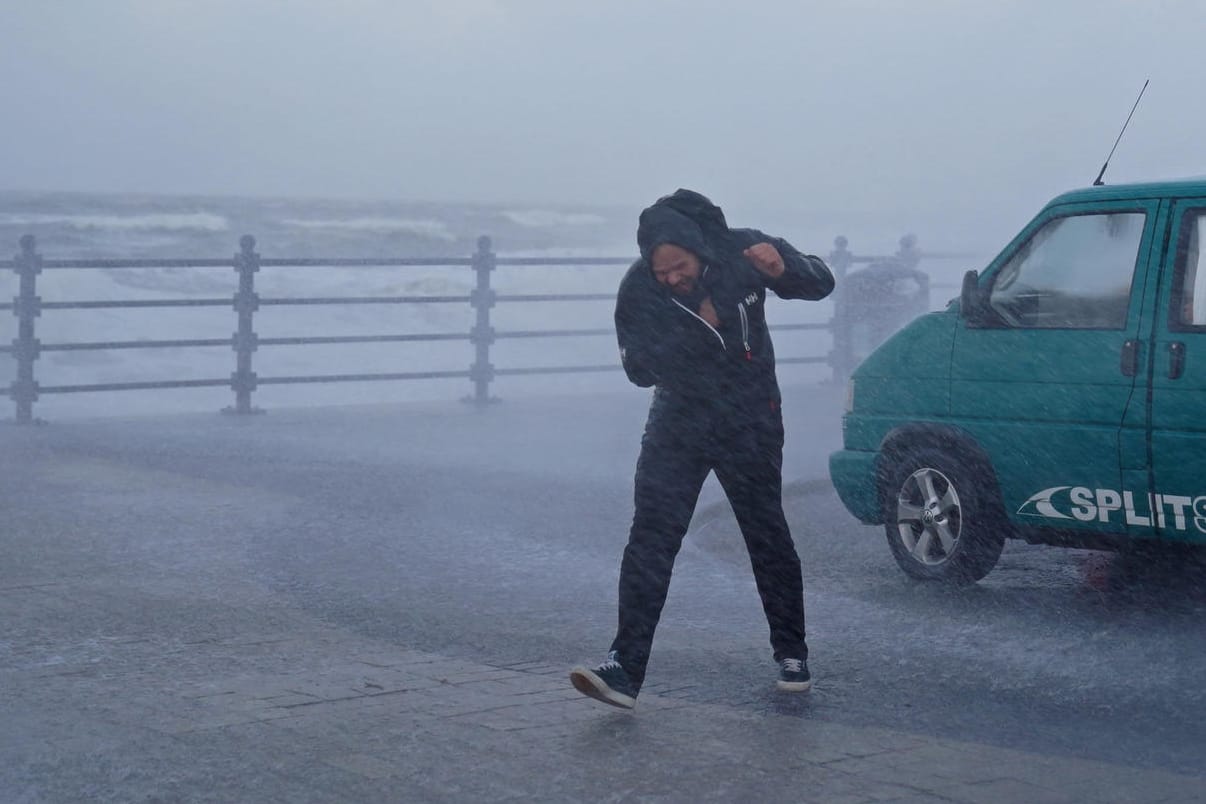 Ein Mann im englischen Porthcawl kämpft gegen den Wind: Von Freitagmittag an drohen an der Nordseeküste Windgeschwindigkeiten von bis zu 160 Kilometern pro Stunde.