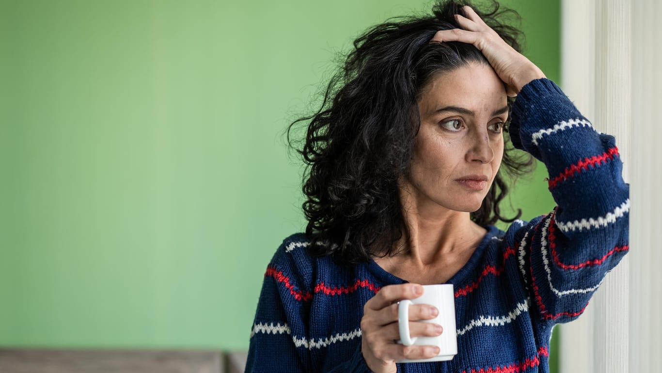 Tired looking woman drinks coffee