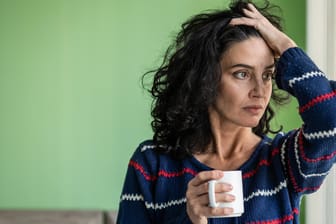 Müde wirkende Frau trinkt Kaffee