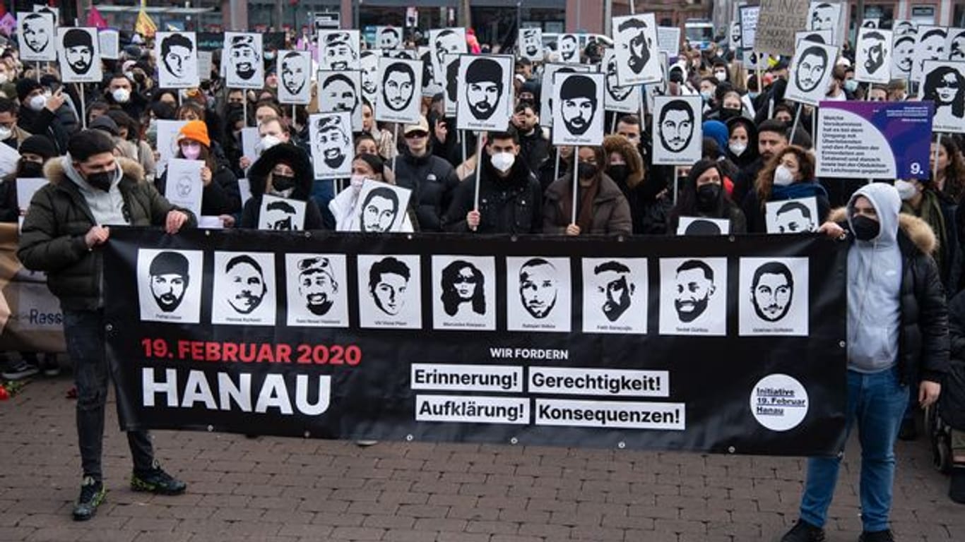 Mit Plakaten und Bildern der Ermordeten erinnern Teilnehmer einer Gedenkveranstaltung auf dem Marktplatz von Hanau an die Opfer der Anschläge von Hanau.
