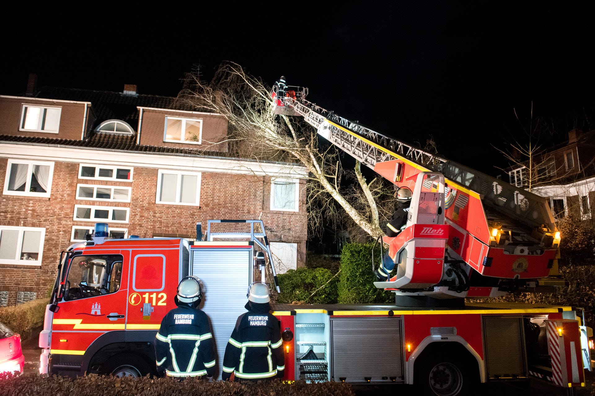 Hamburg: Feuerwehrleute auf einer ausgefahrenen Drehleiter zersägen im Stadtteil Bergedorf einen auf ein Haus gestürzten Baum.