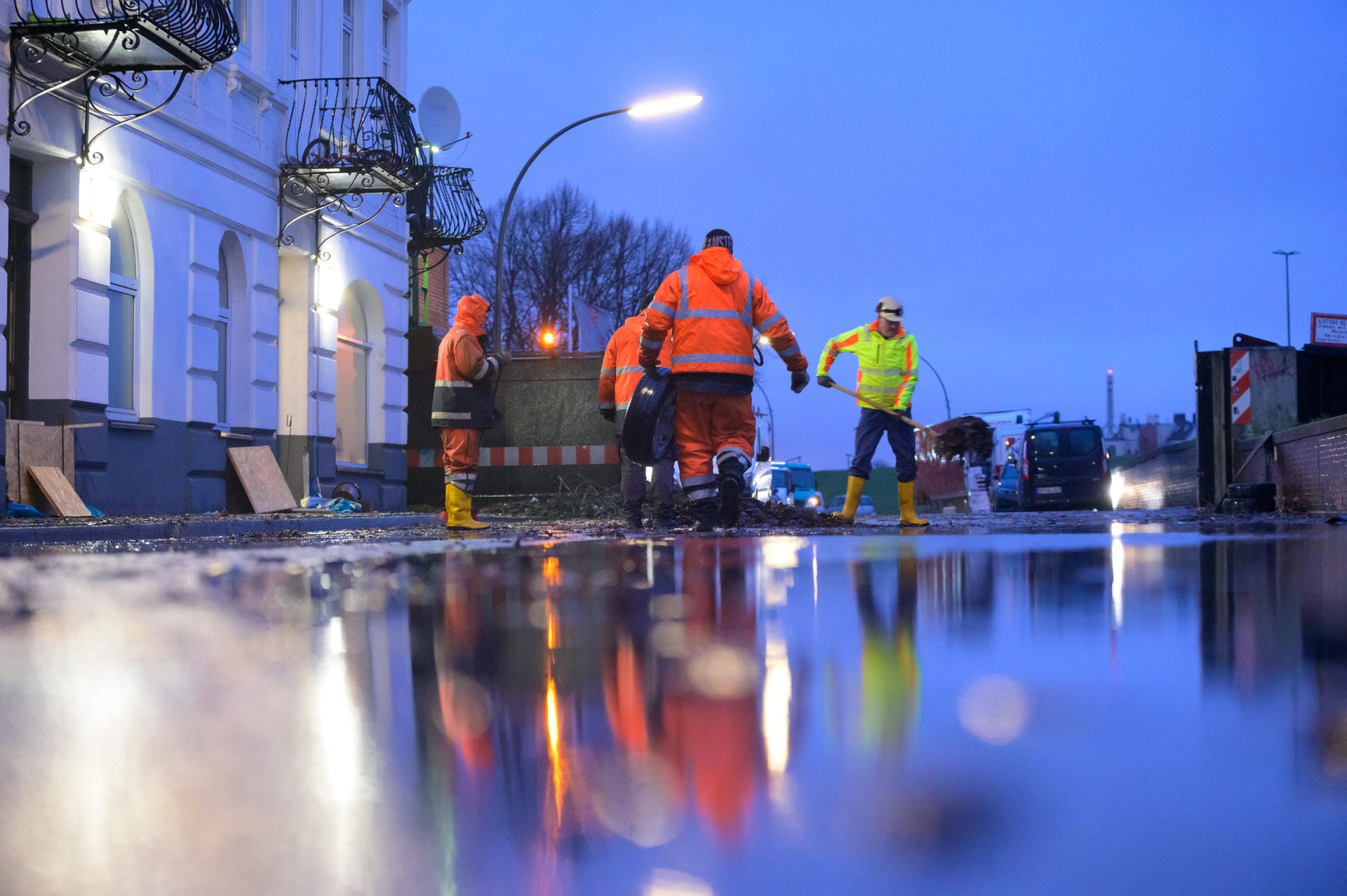 Hamburg: Mitglieder einer Polder-Gemeinschaft reinigen am frühen Morgen eine zuvor überspülte Straße außerhalb des Deiches in Wilhelmsburg.