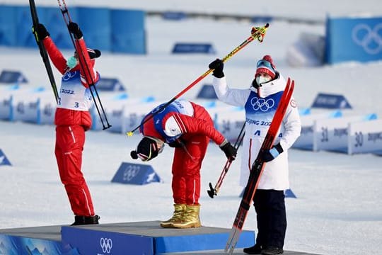 Olympiasieger Alexander Bolschunow feiert seinen Sieg auf dem Treppchen mit goldenen Schuhen.