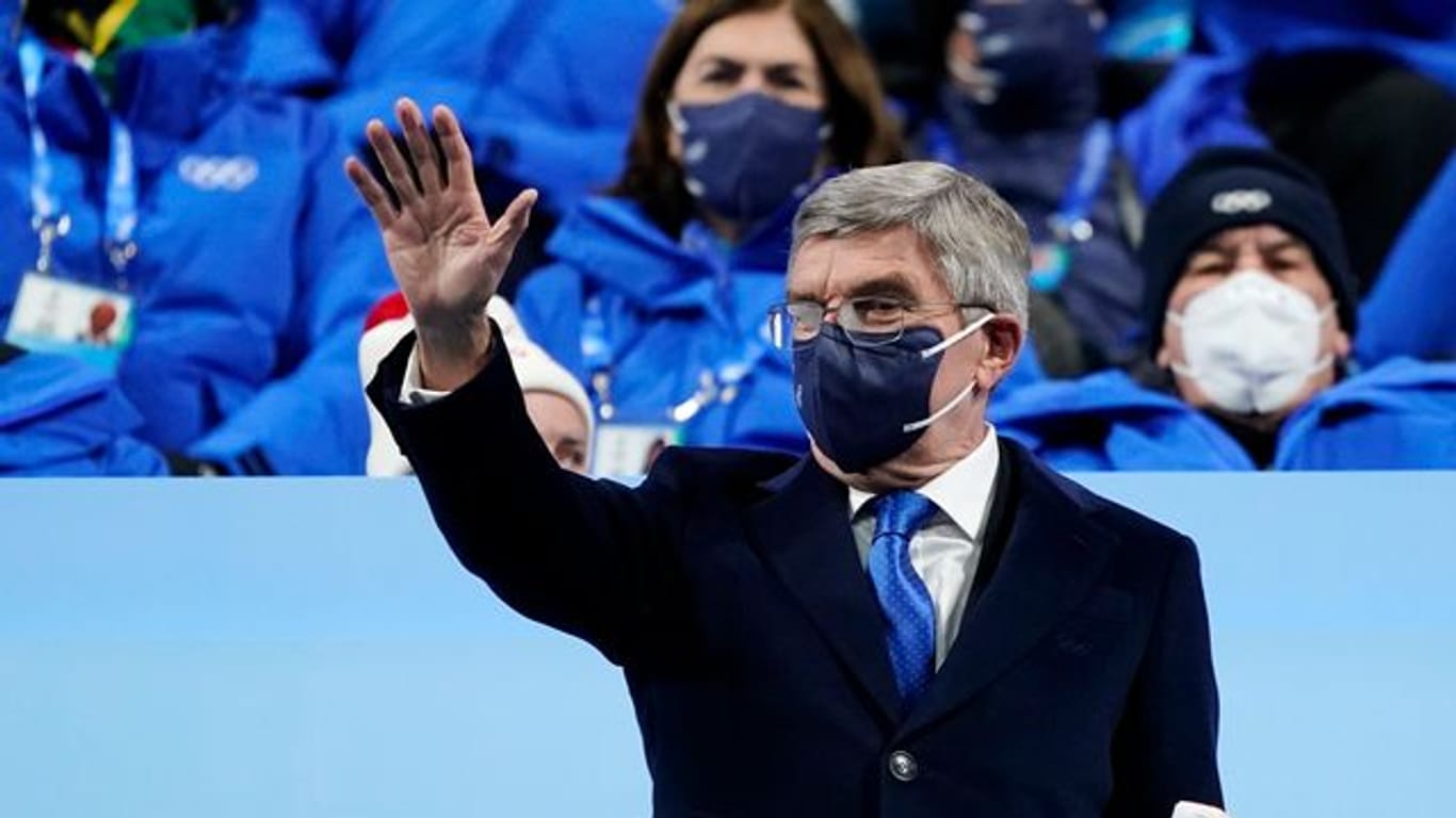 IOC-Präsident Thomas Bach (M) winkt bei der Eröffnungsfeier der Olympischen Winterspiele von der Tribüne aus.