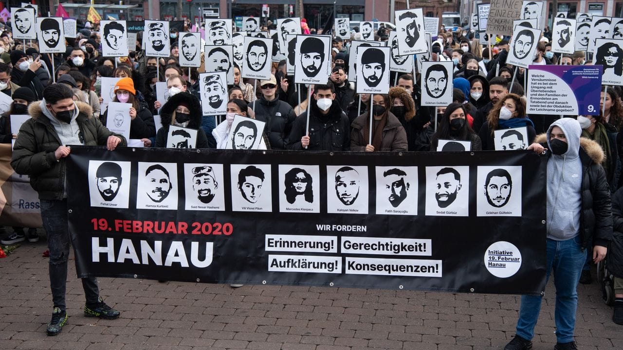 Mit Plakaten und Bildern der Ermordeten erinnern Teilnehmer einer Gedenkveranstaltung auf dem Marktplatz von Hanau an die Opfer der Anschläge von Hanau. Mit Plakaten und Bildern der Ermordeten erinnern Teilnehmer einer Gedenkveranstaltung auf dem Marktplatz von Hanau an die Opfer der Anschläge von Hanau.
