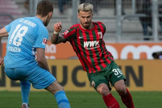 Augsburgs Niklas Dorsch (r) und Freiburgs Nils Petersen kämpfen um den Ball.
