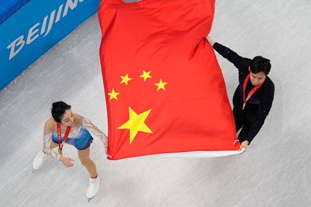 Die Eiskunstläufer Sui Wenjing und Han Cong aus China jubeln mit der chinesischen Fahne.
