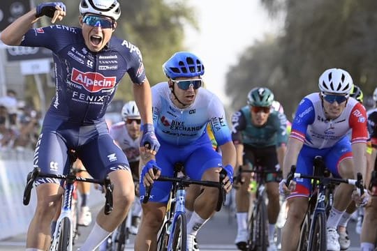 Jasper Philipsen (l) aus Belgien überquert als Erster die Ziellinie beim Auftakt der UAE-Tour und jubelt.