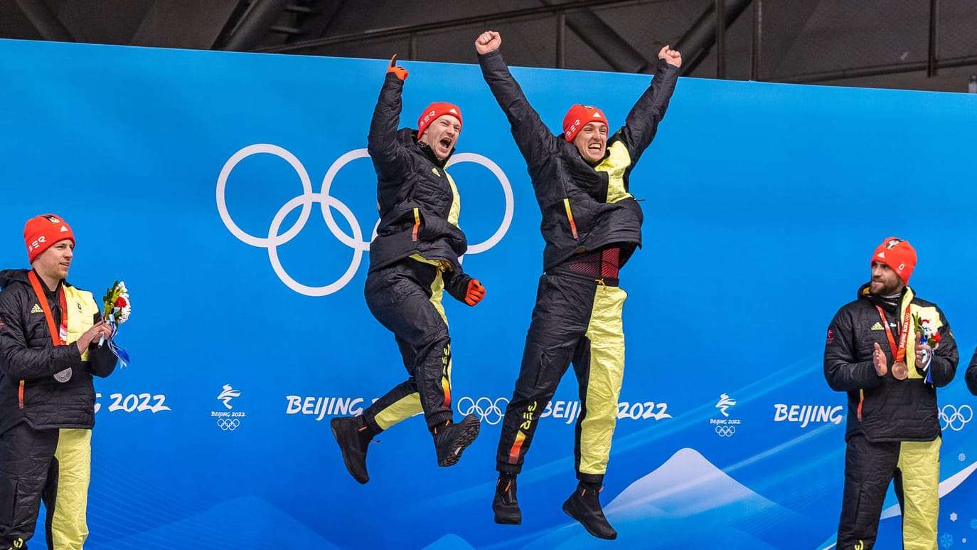 Historischer Olympiamoment: Sechs deutsche Bobfahrer, um Goldmedaillen-Gewinner Francesco Friedrich und Thorsten Margis, auf dem Podium.