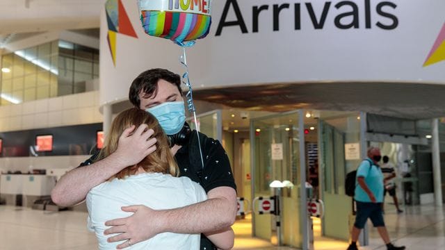 Zwei Personen umarmen sich in der Ankunftshalle am Flughafen Perth.