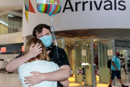 Zwei Personen umarmen sich in der Ankunftshalle am Flughafen Perth.