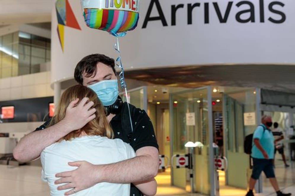 Zwei Personen umarmen sich in der Ankunftshalle am Flughafen Perth.