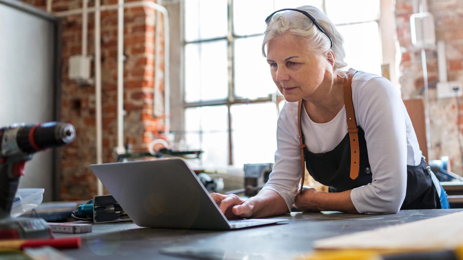 Frau mit Laptop in einer Werkstatt (Symbolbild): Die Umverteilung der Einkommen durch den Fiskus ist zum Teil enorm.