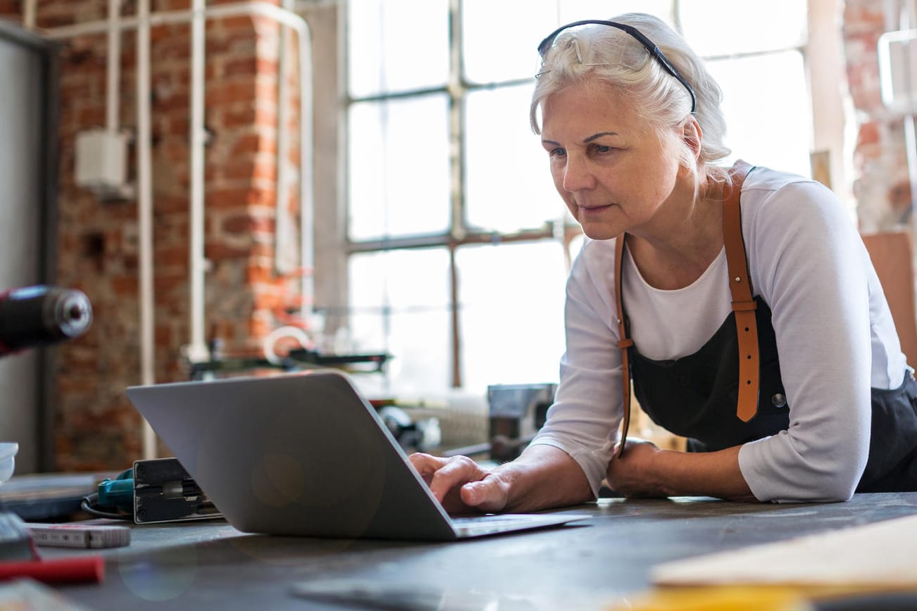 Frau mit Laptop in einer Werkstatt (Symbolbild): Die Umverteilung der Einkommen durch den Fiskus ist zum Teil enorm.