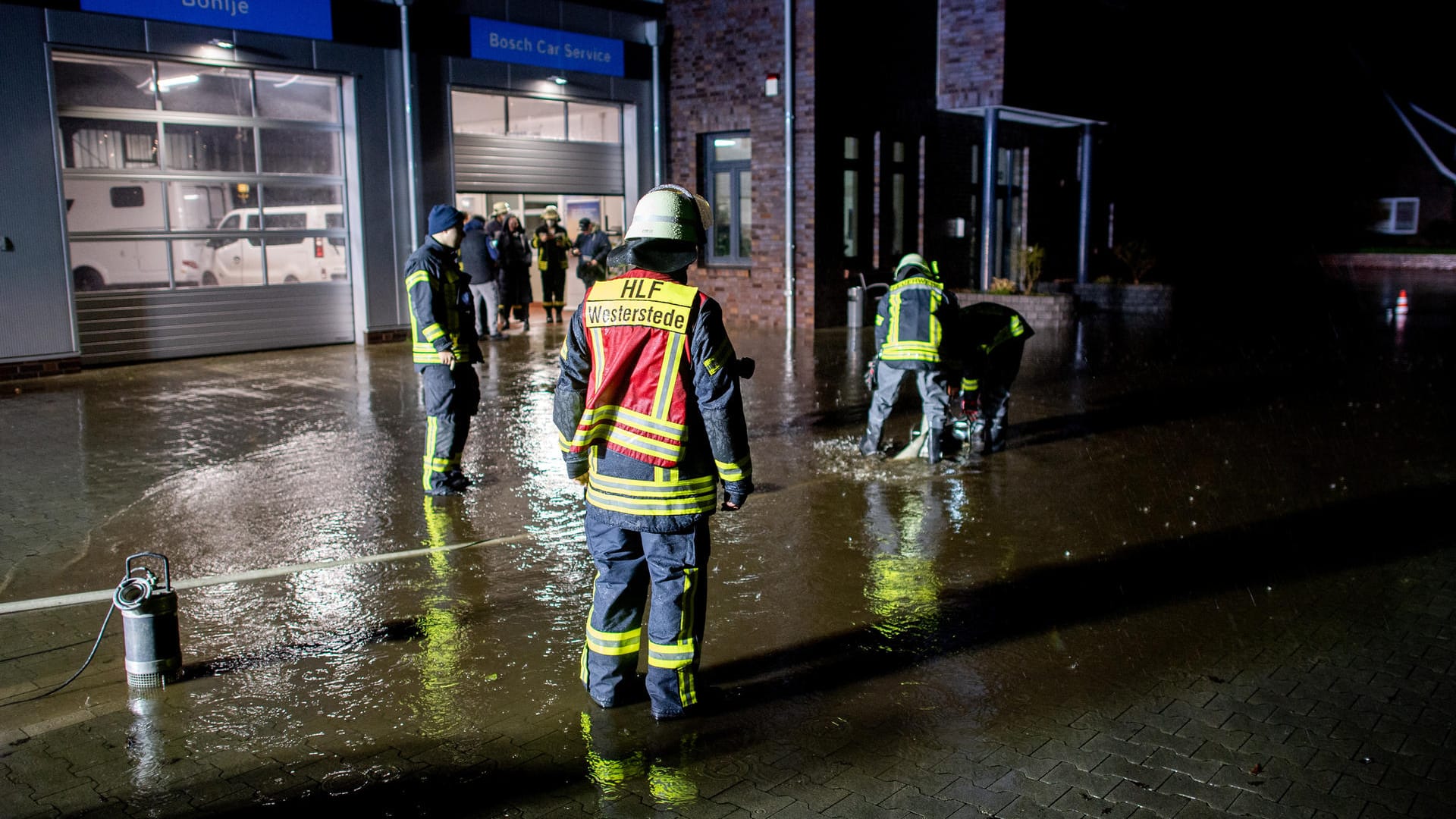 Niedersachsen, Westerstede: Einsatzkräfte der Feuerwehr pumpen das Wasser vom Hof einer Autowerkstatt ab. Durch starken Regenfall droht das Gebäude der Werkstatt überschwemmt zu werden.