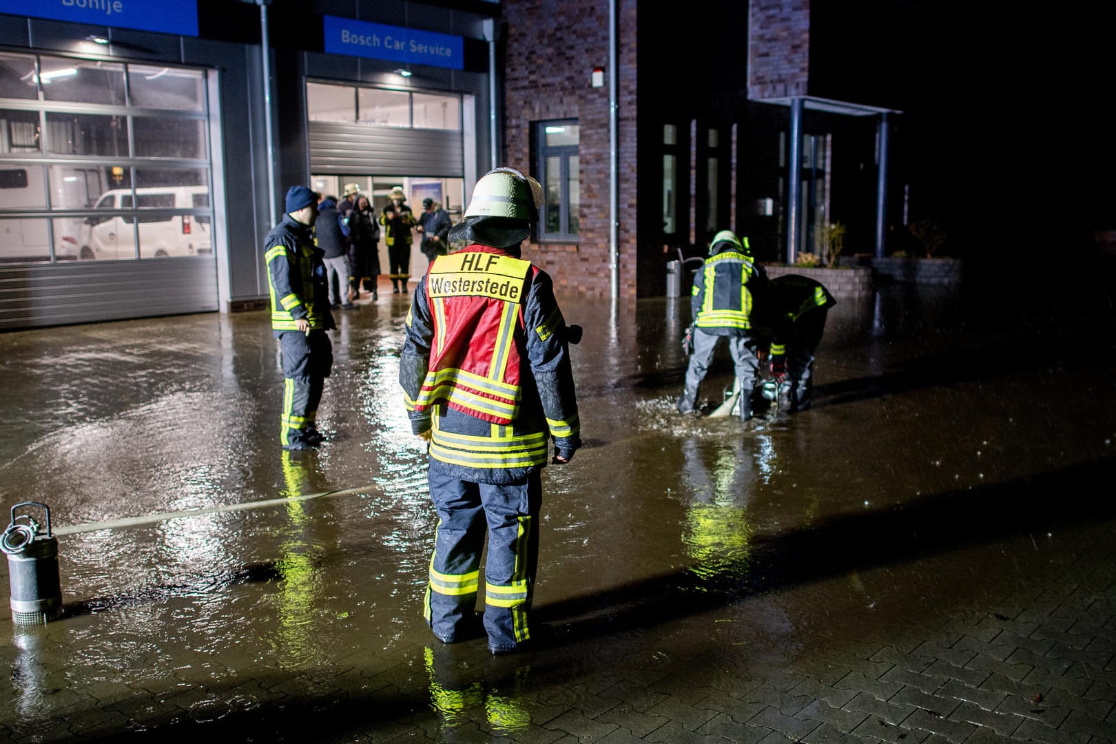 Niedersachsen, Westerstede: Einsatzkräfte der Feuerwehr pumpen das Wasser vom Hof einer Autowerkstatt ab. Durch starken Regenfall droht das Gebäude der Werkstatt überschwemmt zu werden.