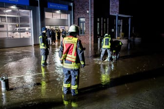 Niedersachsen, Westerstede: Einsatzkräfte der Feuerwehr pumpen das Wasser vom Hof einer Autowerkstatt ab. Durch starken Regenfall droht das Gebäude der Werkstatt überschwemmt zu werden.