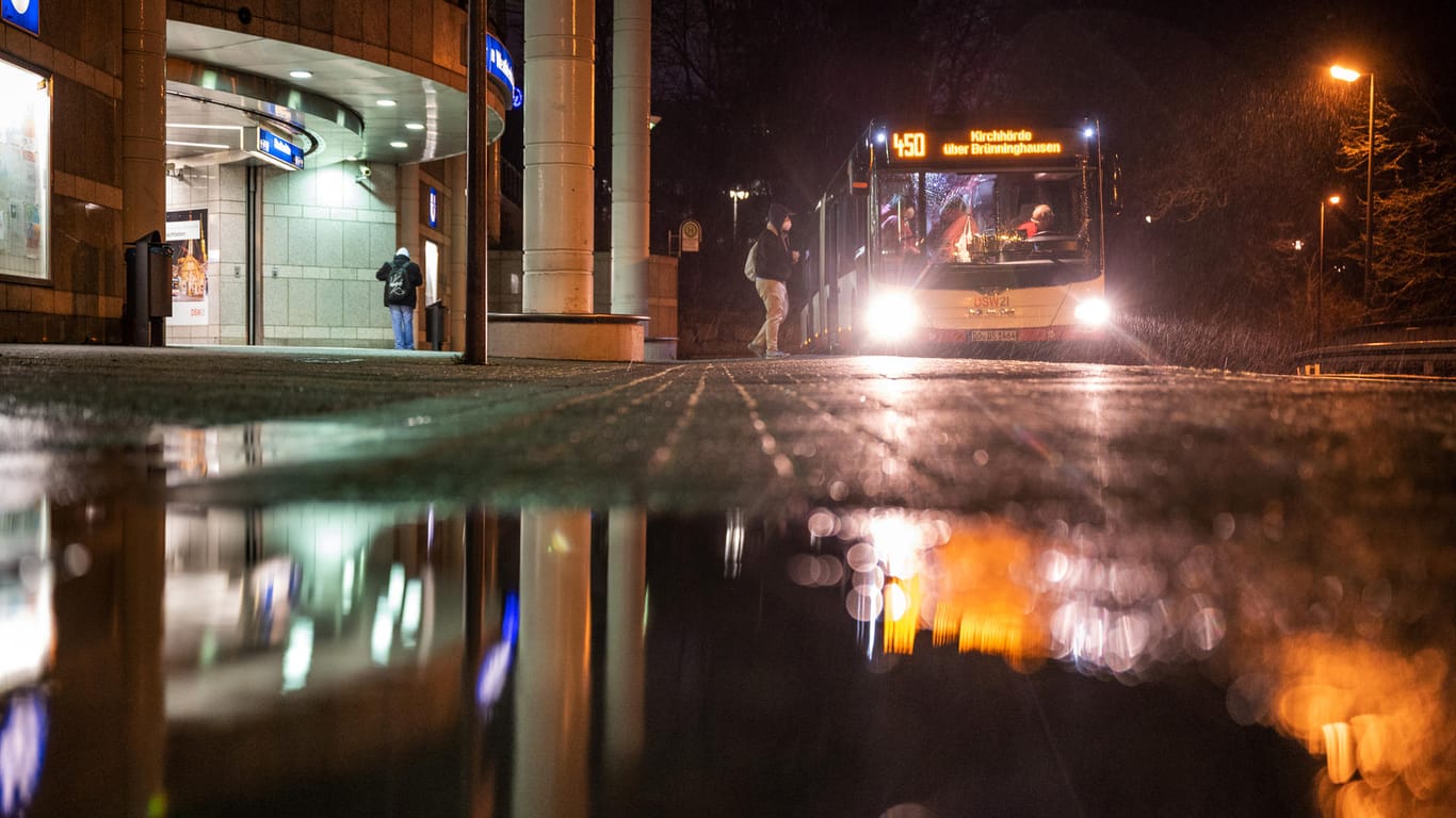 Ein Fahrgast steigt im Regen an einer U-Bahn-Station in Dortmund in einen Linienbus um: Sturm "Antonia" sorgte in NRW für Schäden.
