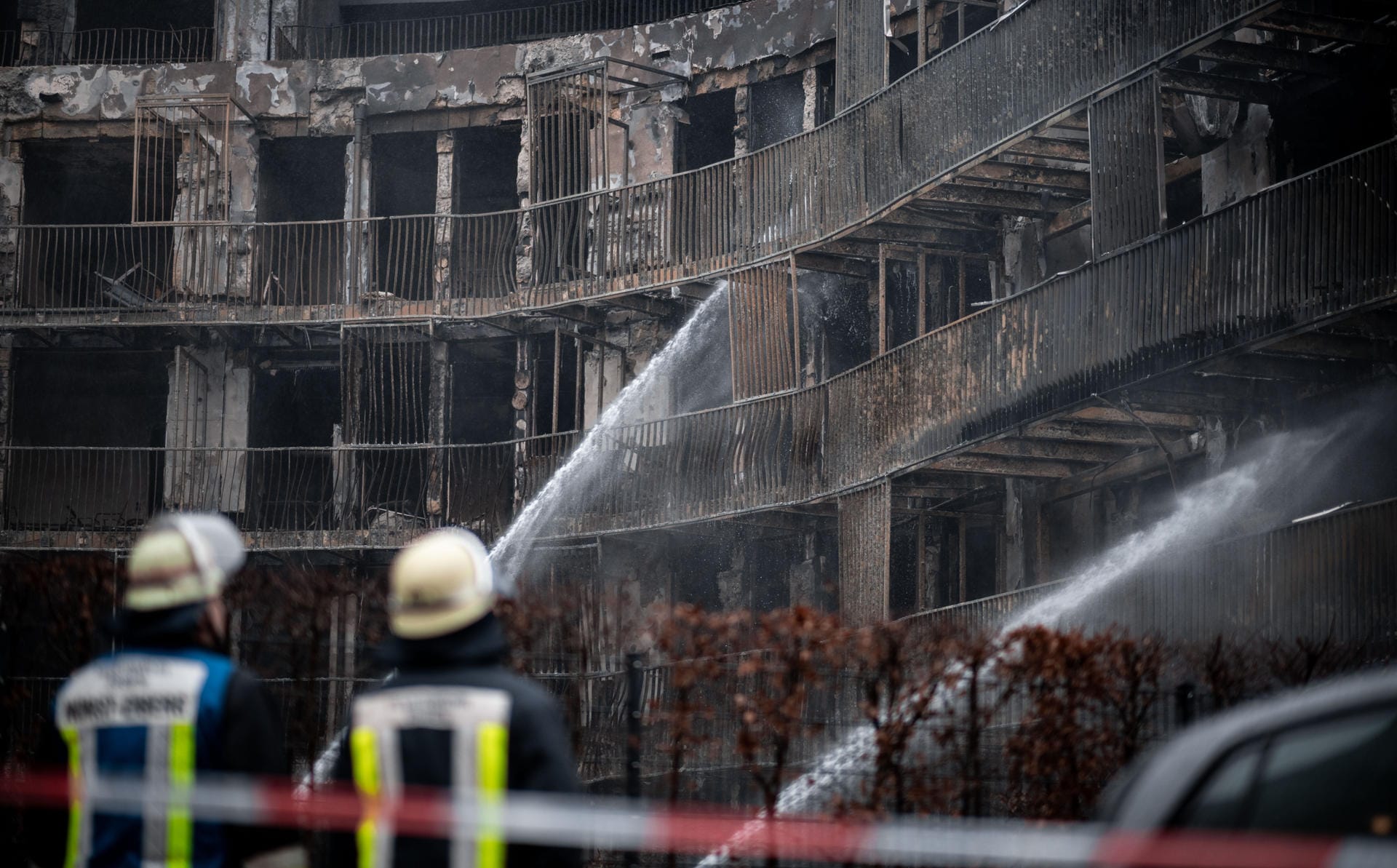 Feuerwehrleute löschen am Tag nach dem Großbrand die letzten Glutnester: 128 Menschen haben ihr Zuhause verloren.