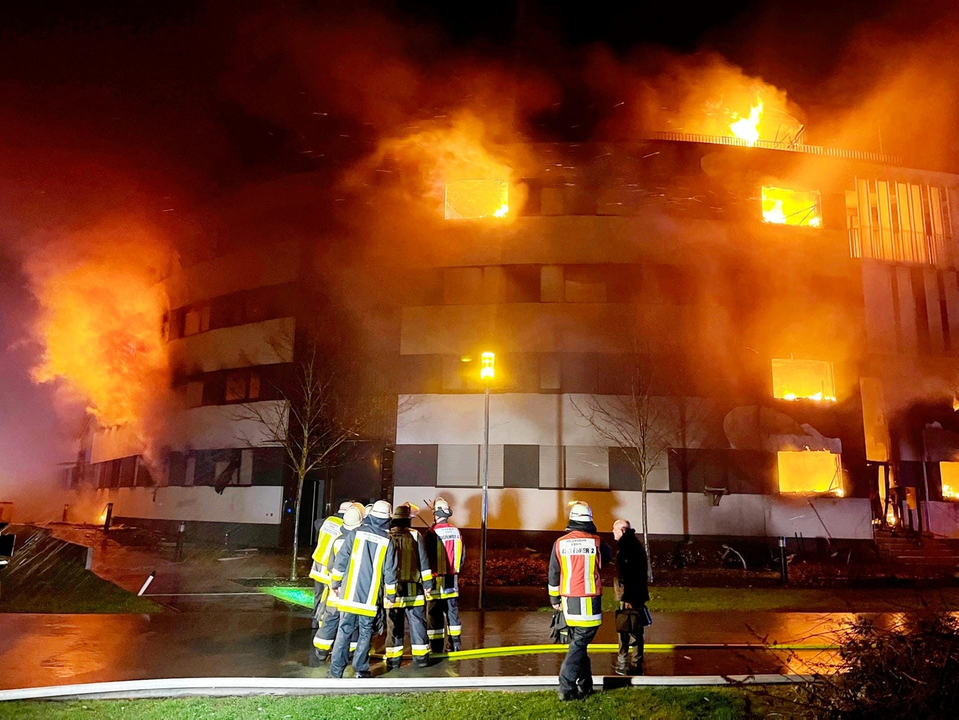 Feuerwehrleute stehen vor dem Gebäude, aus dem die Flammen schlagen: Rund 150 Einsatzkräfte kämpften bis zum Morgen gegen den Brand an.