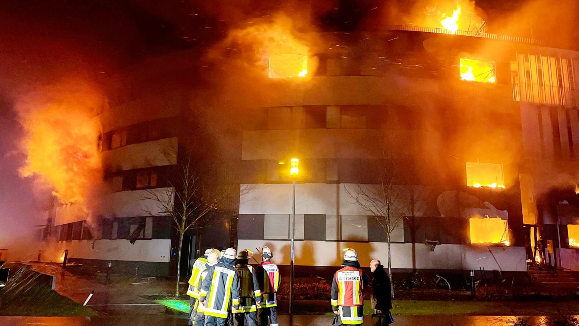 Feuerwehrleute stehen vor dem Gebäude, aus dem die Flammen schlagen: Rund 150 Einsatzkräfte kämpften bis zum Morgen gegen den Brand an.