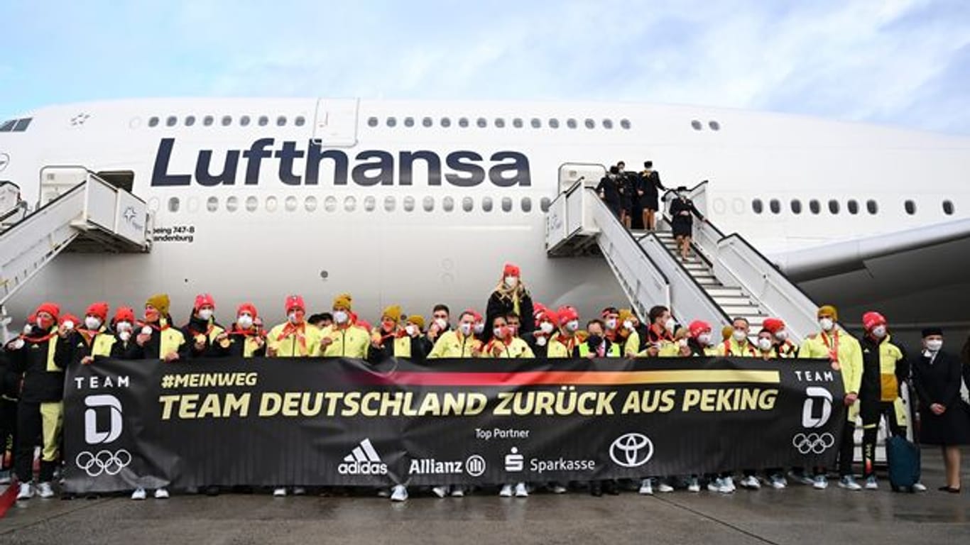 Das deutsche Olympia-Team steht bei der Rückkehr von den Winterspielen auf dem Frankfurter Flughafen hinter einem Plakat: "Team Deutschland zurück aus Peking".