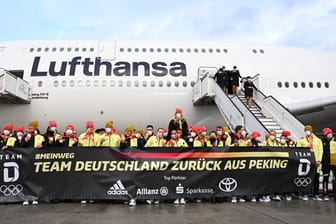 Das deutsche Olympia-Team steht bei der Rückkehr von den Winterspielen auf dem Frankfurter Flughafen hinter einem Plakat: "Team Deutschland zurück aus Peking".