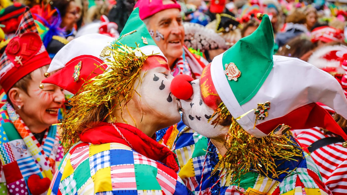 Zwei verkleidete Menschen geben sich einen Kuss (Symbolbild): Das "Bützen" gehört eigentlich fest zum Karneval in Köln dazu. Kölns OB Henriette Reker mahnt trotz weitreichender Lockerungen aber zur Zurückhaltung.