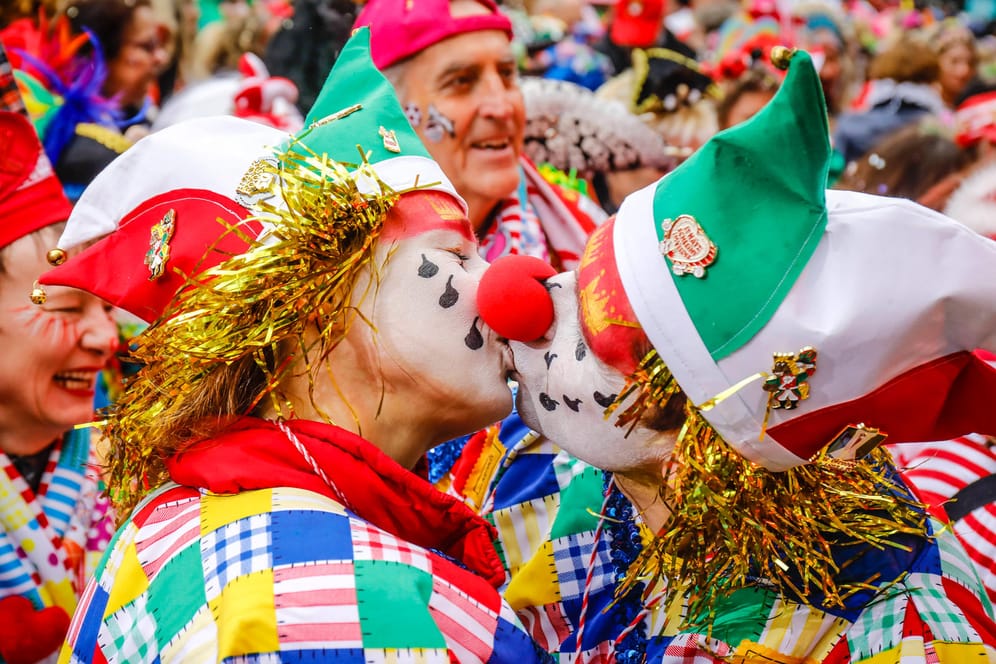 Zwei verkleidete Menschen geben sich einen Kuss (Symbolbild): Das "Bützen" gehört eigentlich fest zum Karneval in Köln dazu. Kölns OB Henriette Reker mahnt trotz weitreichender Lockerungen aber zur Zurückhaltung.