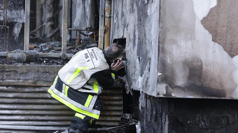 Ein Feuerwehrmann macht ein Bild mit dem Handy von der Zerstörung: Das Gebäude muss nach dem Brand abgerissen werden.