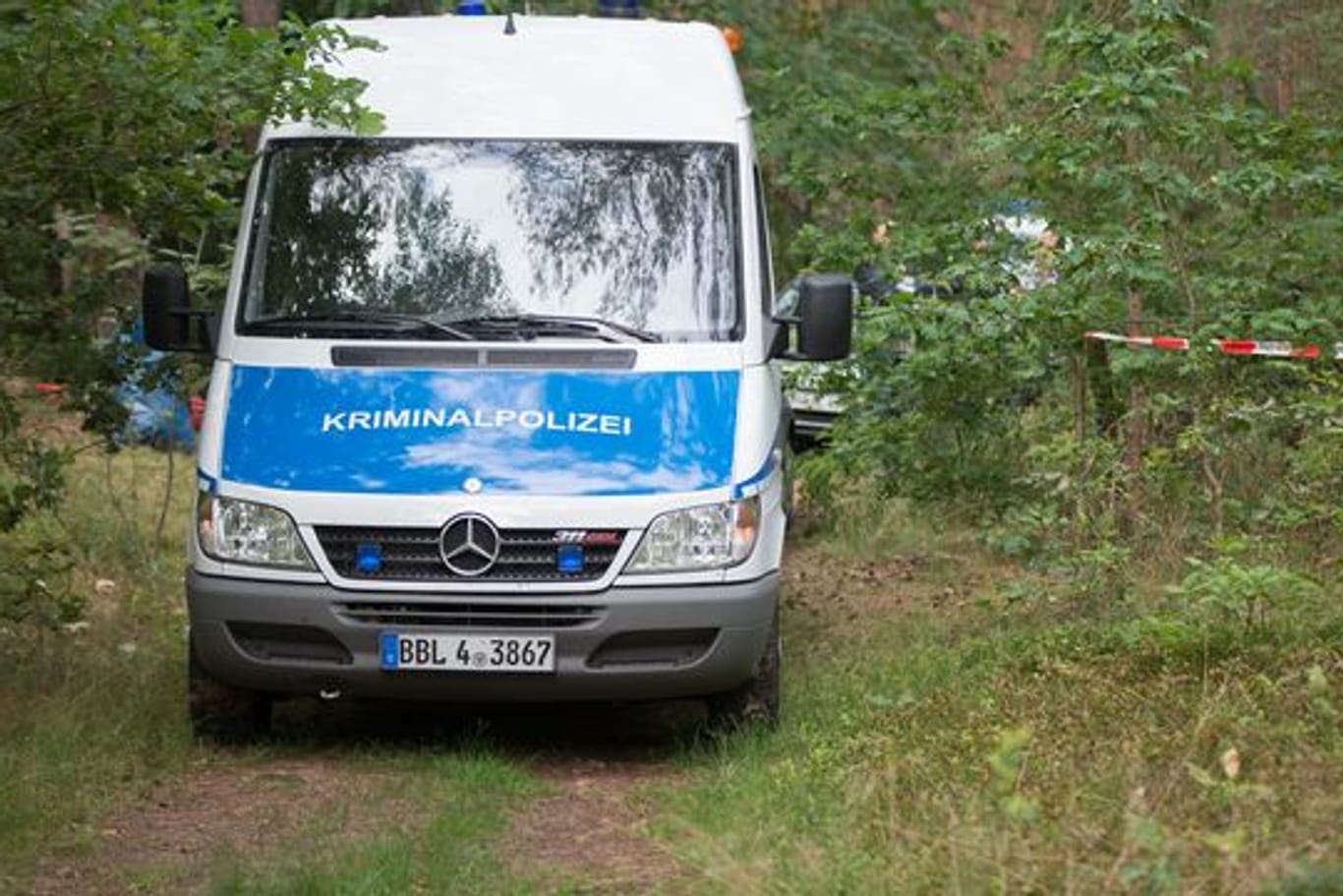Ein Wagen der Kriminalpolizei steht im Juli 2021 in der Nähe des Tatorts in einem Wald bei Oranienburg.