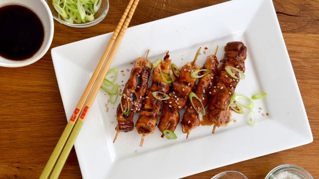 Die Teriyaki-Soße aus Sojasoße, Mirin und Sake und eine große Portion Zucker sorgen dafür, dass das Fleisch der Yakitori-Spieße schön glänzt und beim Grillen zart bleibt.