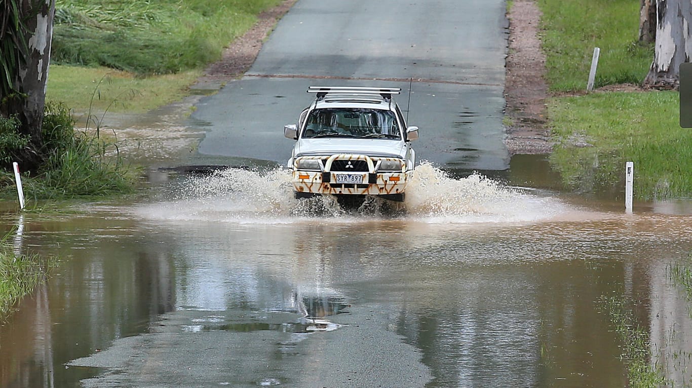 Ein Auto fährt in Australien im Hochwasser einer überschwemmten Straße: Anwohner wurden aufgefordert, möglichst zuhause zu bleiben.