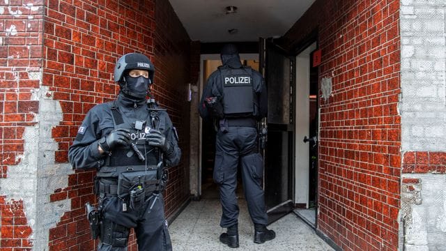 Polizisten stehen in einem Hauseingang im Stadtteil Laar.