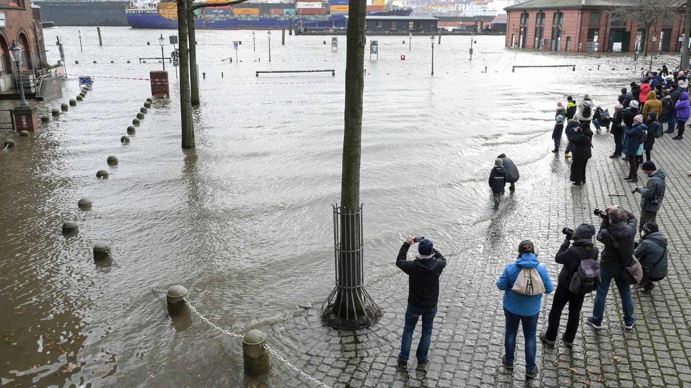 Fotografierende Bürger stehen am Rand des Hochwassers in Hamburg (Archivbild): In den umliegenden Läden bricht das Geschäft während der Sturmfluten ein.