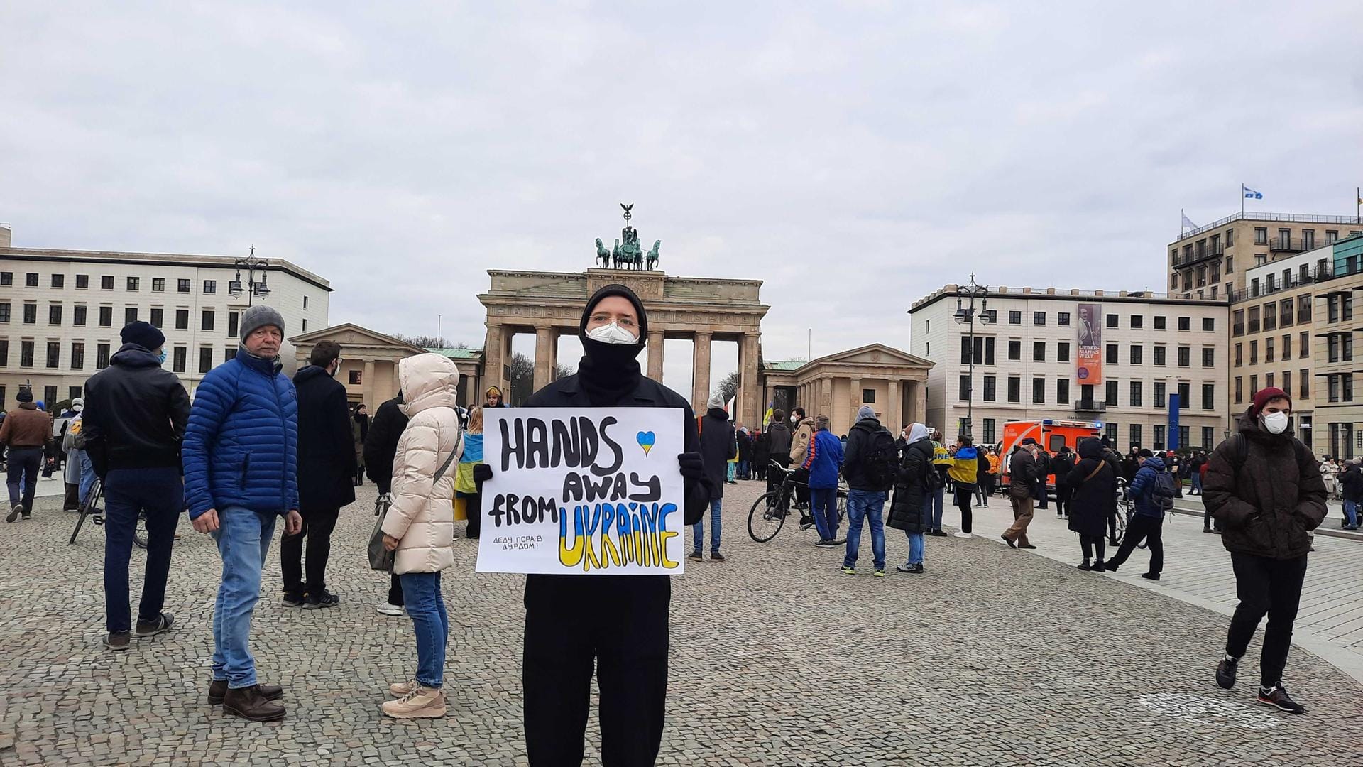 Simon hält ein Schild mit der Aufschrift "Hands away from Ukraine".