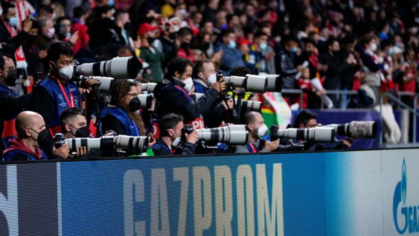 Bei einem Spiel der Champions League stehen Fotoreporter hinter einer Bande mit dem Schriftzug von Gazprom.