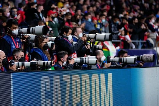 Bei einem Spiel der Champions League stehen Fotoreporter hinter einer Bande mit dem Schriftzug von Gazprom.